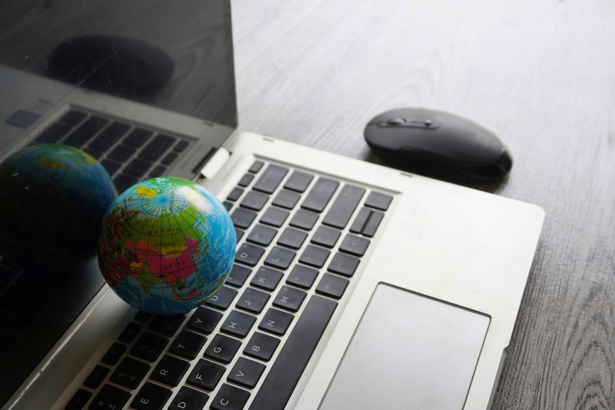 Close up image of globe, laptop keyboard and computer mouse.